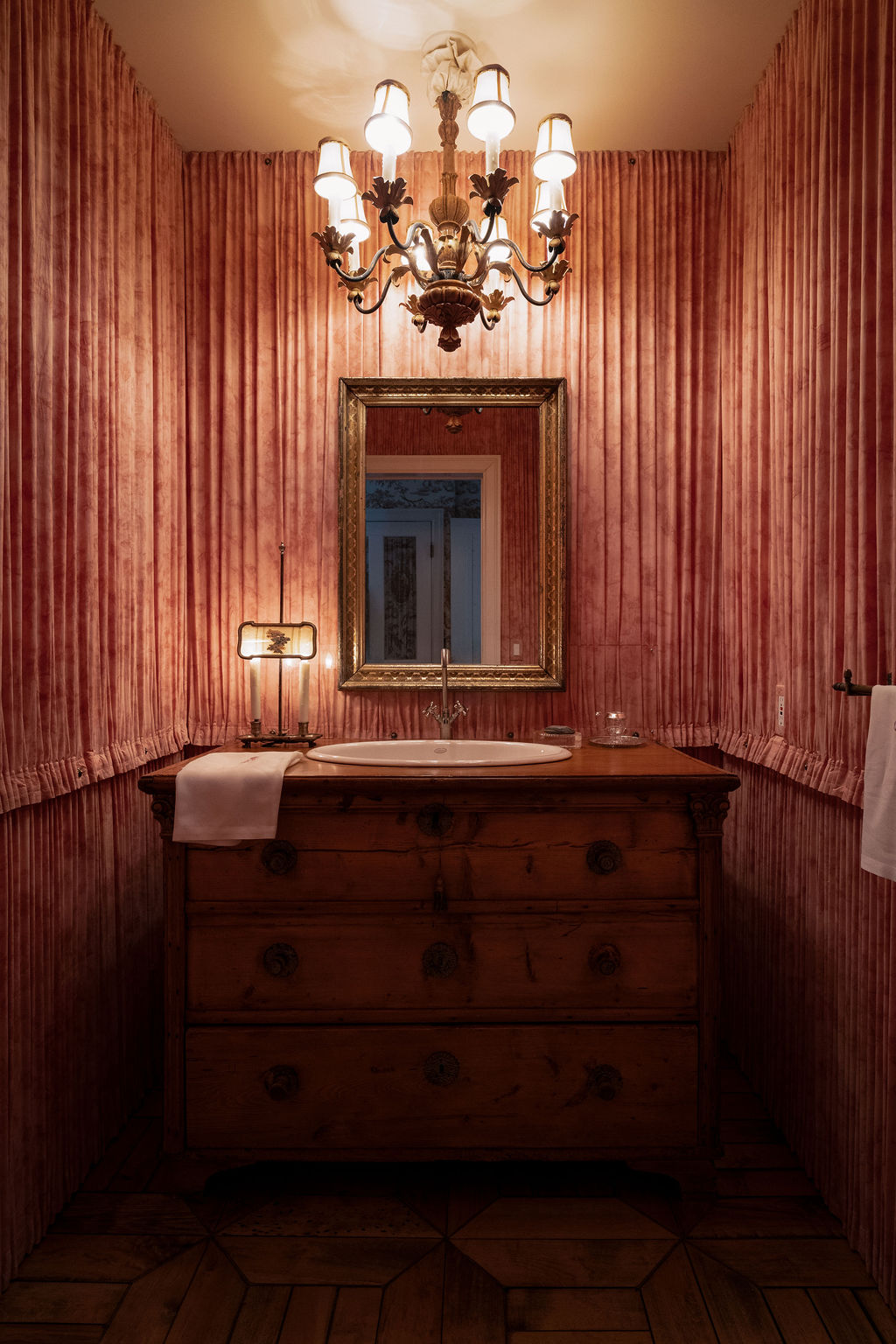 witness-locations-chalet-tournesol-idyllwild-powder-room-pleated-rose-fabric-walls-chandelier-antique-commode-sink