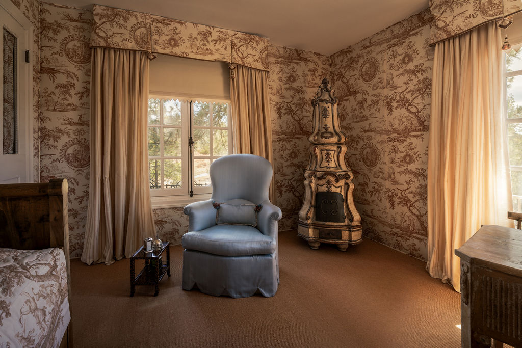 witness-locations-chalet-tournesol-idyllwild-toile-bedroom-blue-slipper-chair-painted-tile-stove